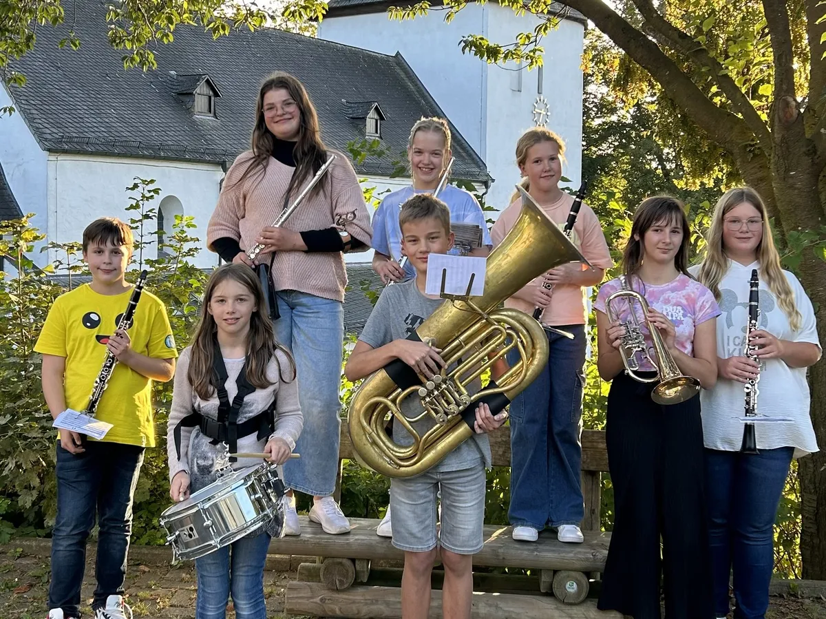Jungmusikerinnen und Jungmusiker mit ihren Instrumenten vor der Kirche